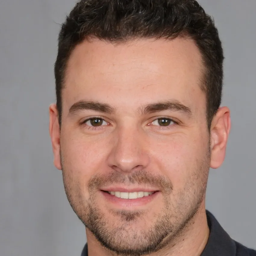 Michael Hayes, a confident man with short dark hair and a trimmed beard, posing in front of a neutral grey background.